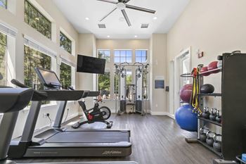 A gym with a treadmill and weights and a tv